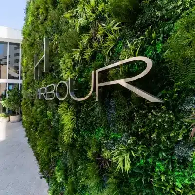 A vibrant and inviting entrance features a vertical garden wall filled with lush greenery from the Large Grasses Texture Box, enhanced by a sleek modern metallic sign bearing the text HARBOUR.