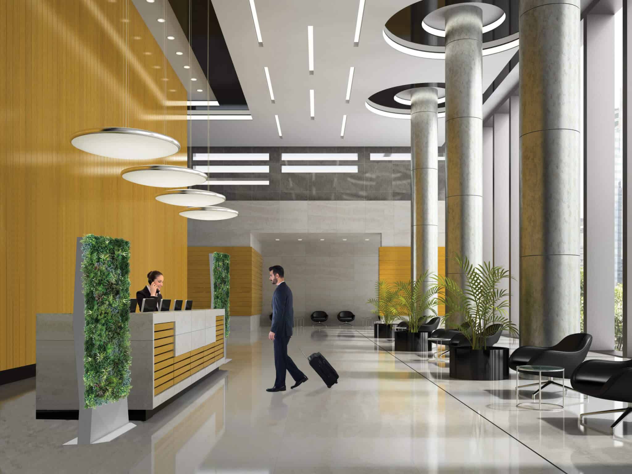 A man with a suitcase approaches a reception desk in a modern, brightly lit hotel lobby. The area features sleek furniture, tall columns, and Modular Green Wall Partitions.